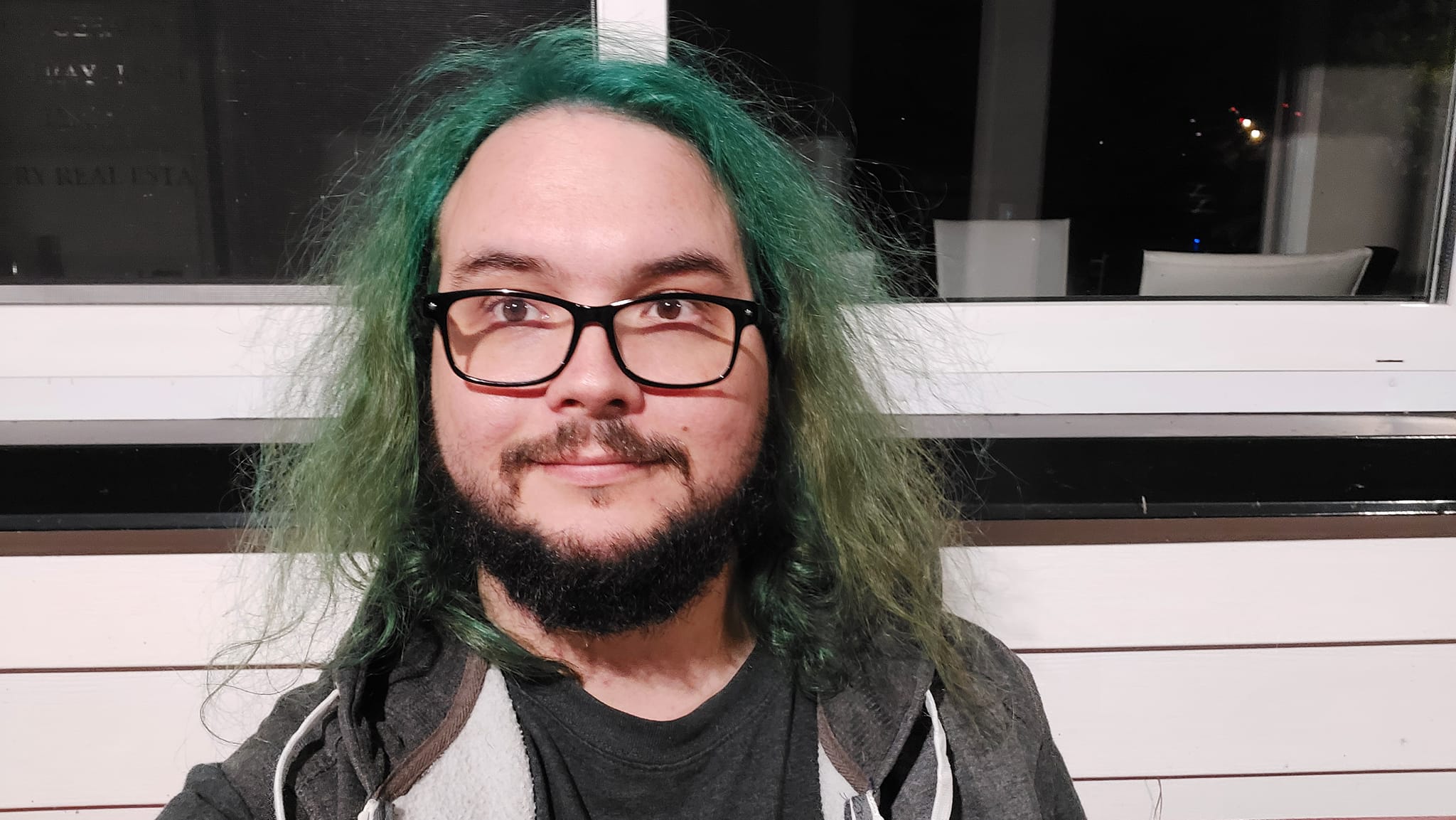 A man with green hair is outside after dark, Photo 6